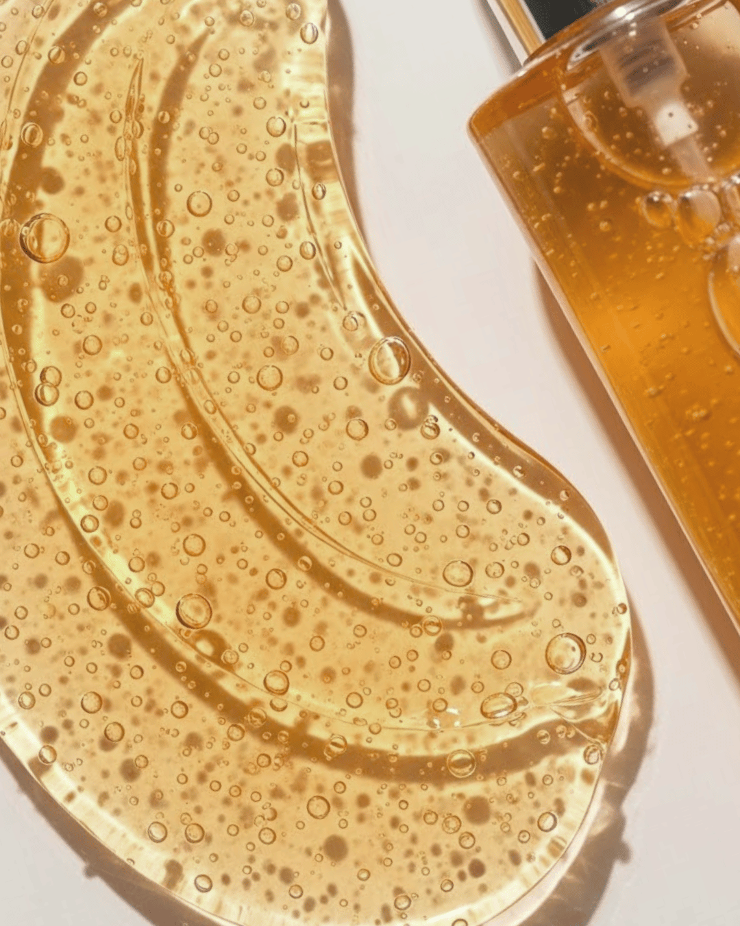 Close-up of a skincare product with a gel-like texture and bubbles, next to a bottle of the product.